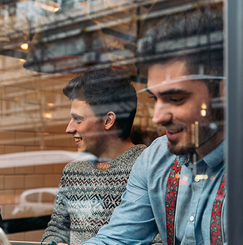 Essstörungen bei Jungen und Männern Blick durchs Fenster auf zwei Männer in einem Cafe